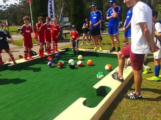 Kids playing soccer billiards on sunny day