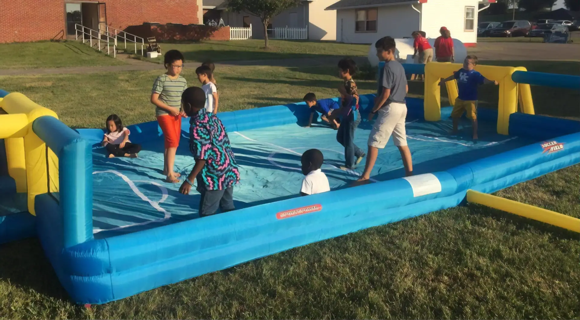 A group of children playing soccer on an inflatable pool toy