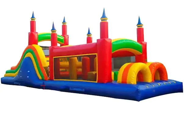 Colorful inflatable bouncy castle with red, yellow, green, and blue sections, featuring arches, tunnels, and turrets on a plain white background